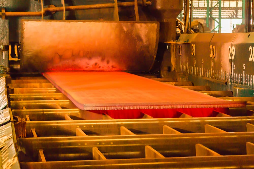 Metal plates are being rolled to spec on a hot rolling machine.